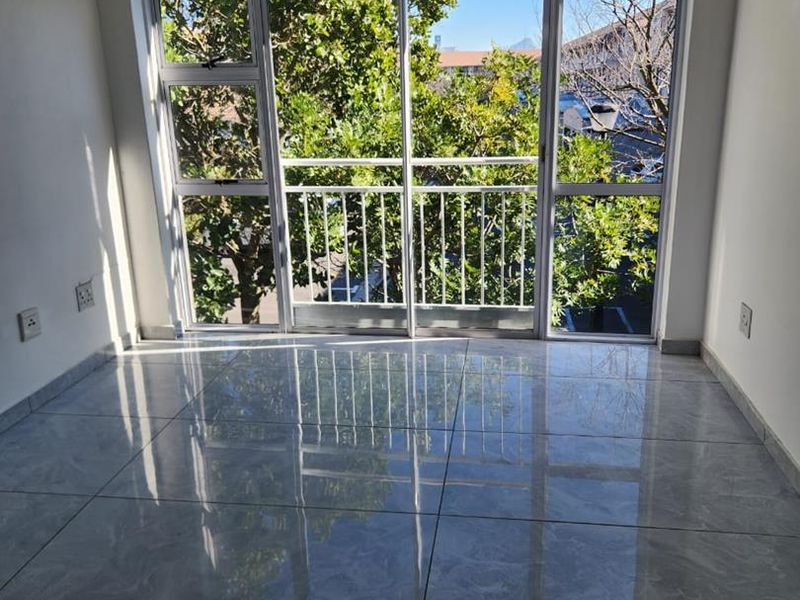 Bright and spacious living area featuring large sliding glass doors, polished tiled flooring, and a neutral aesthetic, offering a clean canvas for interior design.