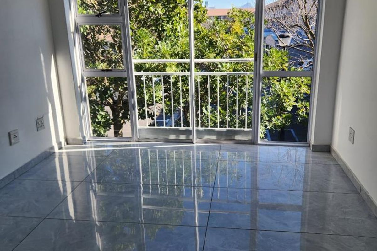 Bright and spacious living area featuring large sliding glass doors, polished tiled flooring, and a neutral aesthetic, offering a clean canvas for interior design.
