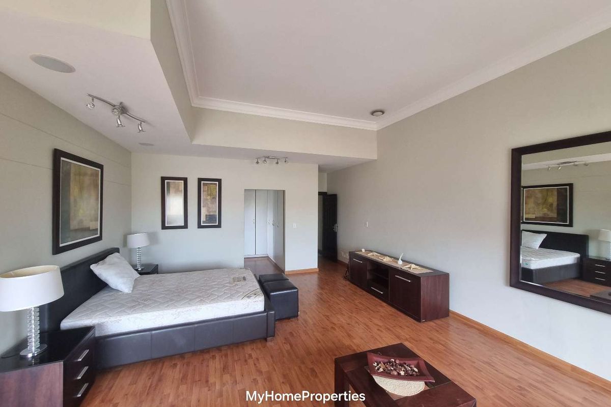 Spacious bedroom featuring laminate flooring, built-in cupboards, and recessed ceiling lighting with decorative cove molding.