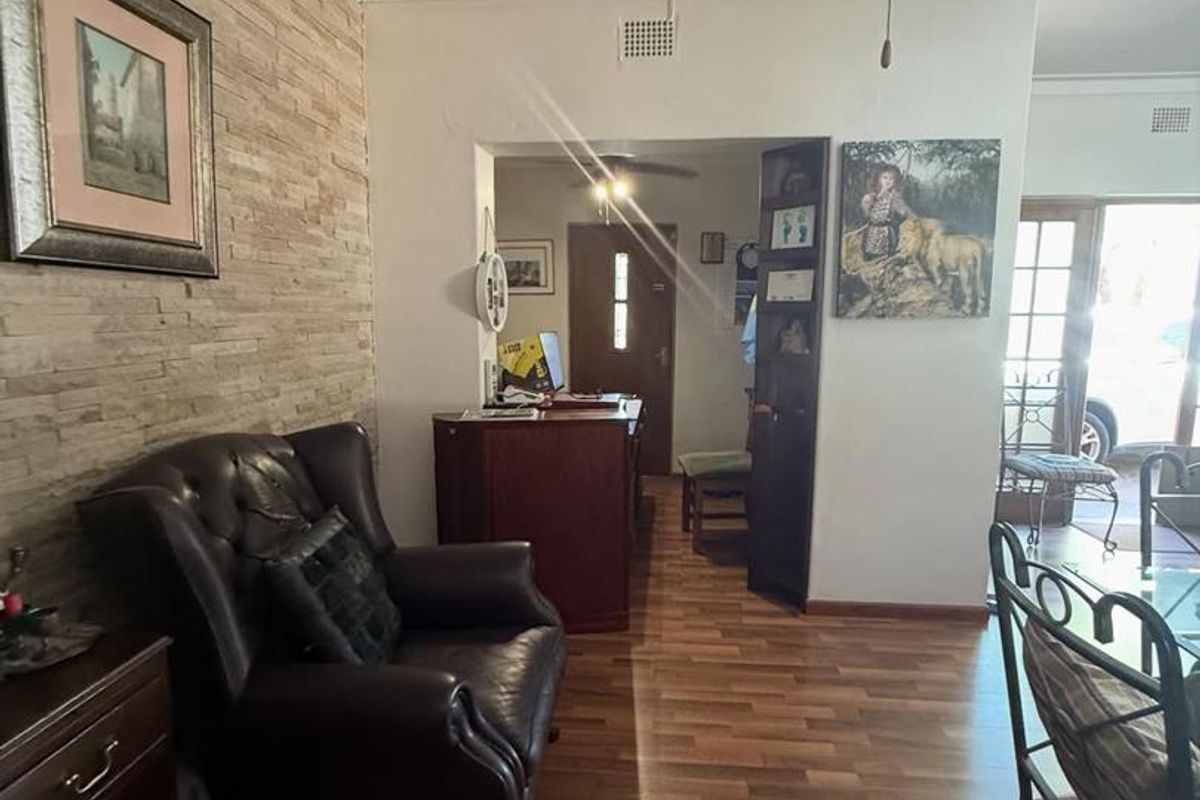 A view of a reception or waiting area featuring wood-look laminate flooring, a textured stone feature wall, and a ceiling fan.
