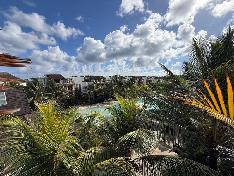 Elevated view overlooking the complex swimming pool and lush tropical landscaped gardens.