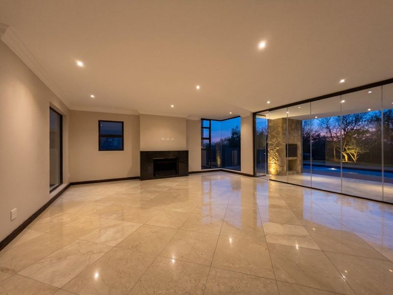 Spacious, modern living area featuring polished marble floors, a built-in fireplace, and expansive glass sliding doors opening to an outdoor pool area.