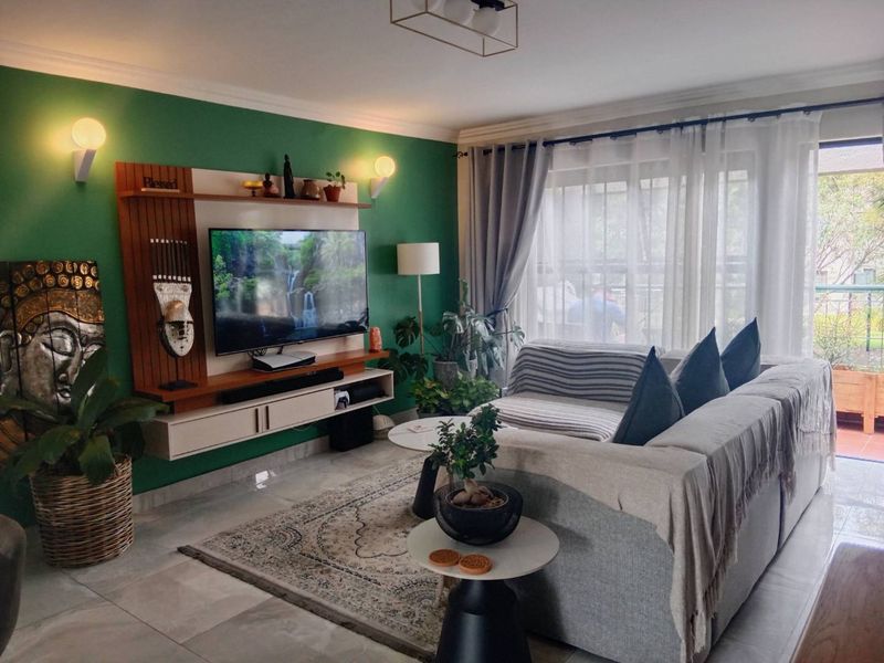 A well-maintained living room featuring a built-in media console, tiled flooring, and large sliding glass doors that provide access to an outdoor balcony area.