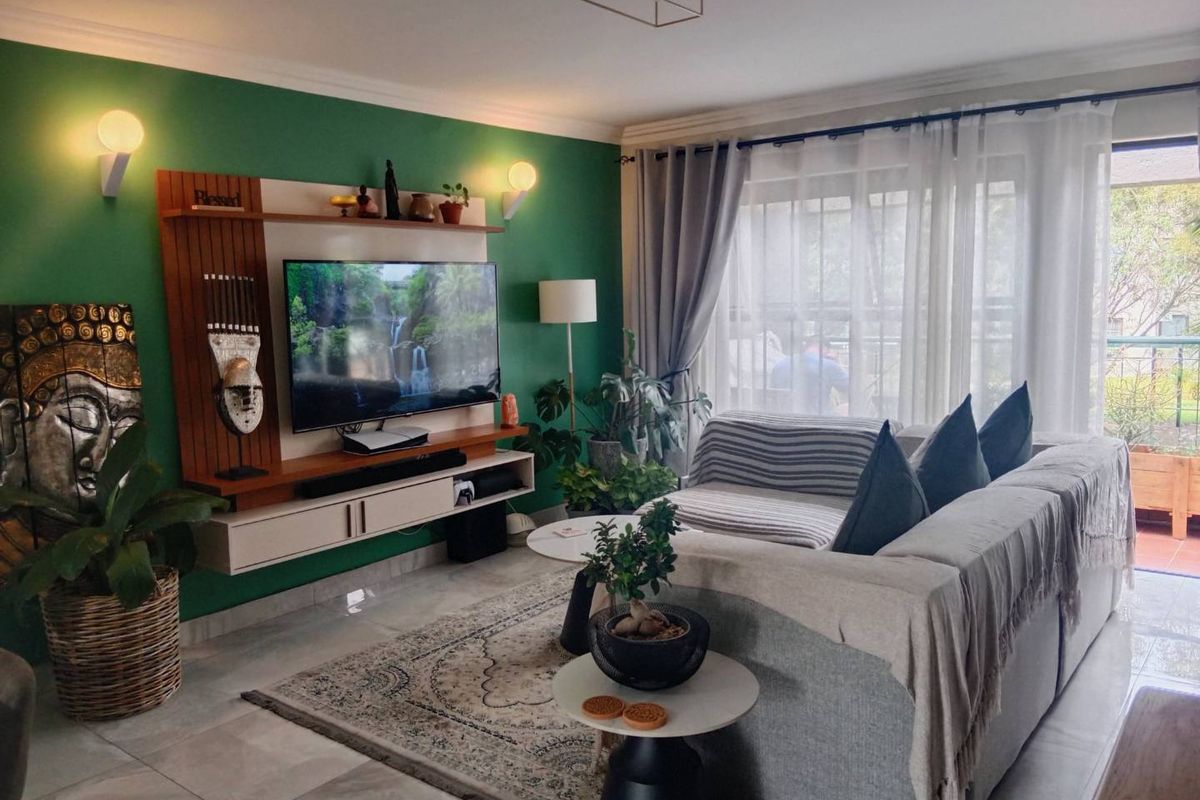 A well-maintained living room featuring a built-in media console, tiled flooring, and large sliding glass doors that provide access to an outdoor balcony area.