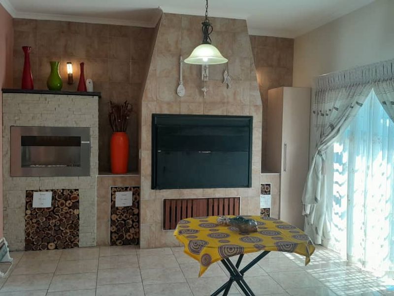 Living room featuring a prominent tiled fireplace with built-in wood storage and large sliding glass doors providing natural light.