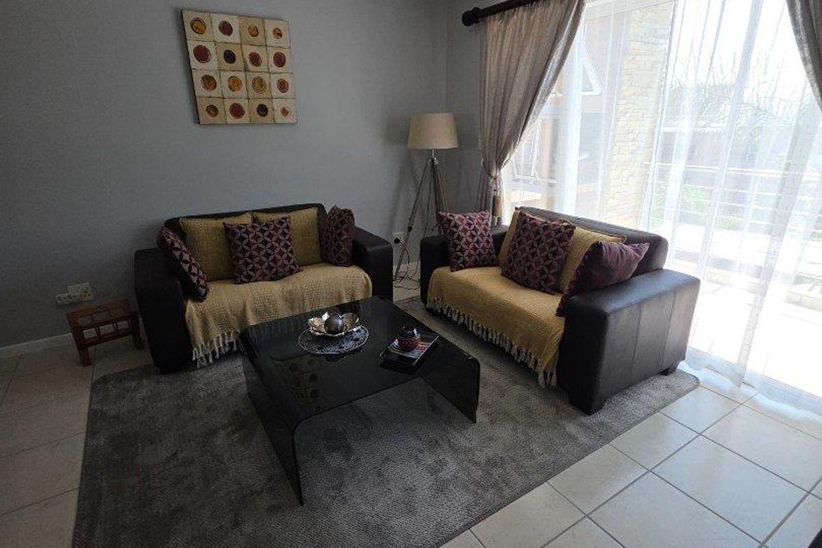 A comfortable living room featuring tiled flooring, a ceiling-mounted light fixture, and large sliding glass doors that provide access to an outdoor area.