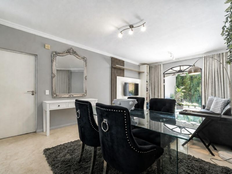 A well-maintained living area featuring a built-in media unit, coving, and a large arch-top sliding glass door providing access to the outdoors.