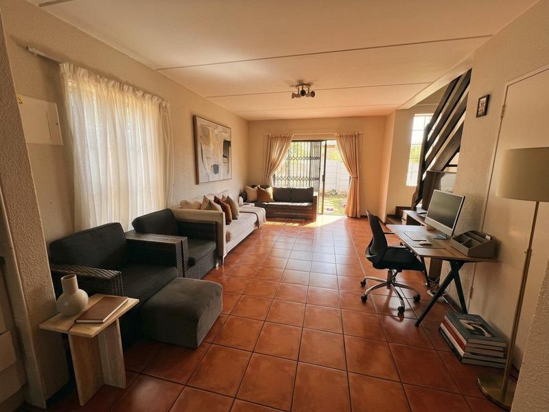 Spacious living area featuring terracotta-style tiled flooring, a staircase, and a sliding glass door providing access to the rear outdoor space.