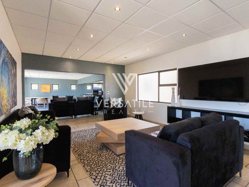Spacious living area featuring tiled flooring, recessed lighting, and a suspended ceiling, with an open-plan flow into the adjacent room.