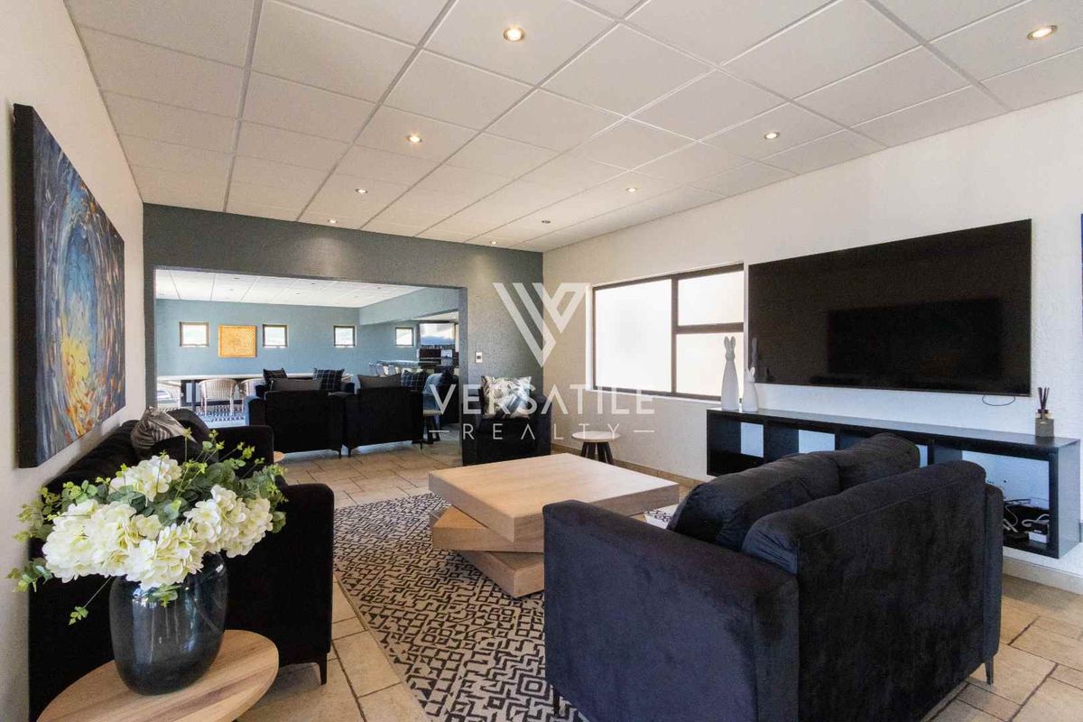 Spacious living area featuring tiled flooring, recessed lighting, and a suspended ceiling, with an open-plan flow into the adjacent room.
