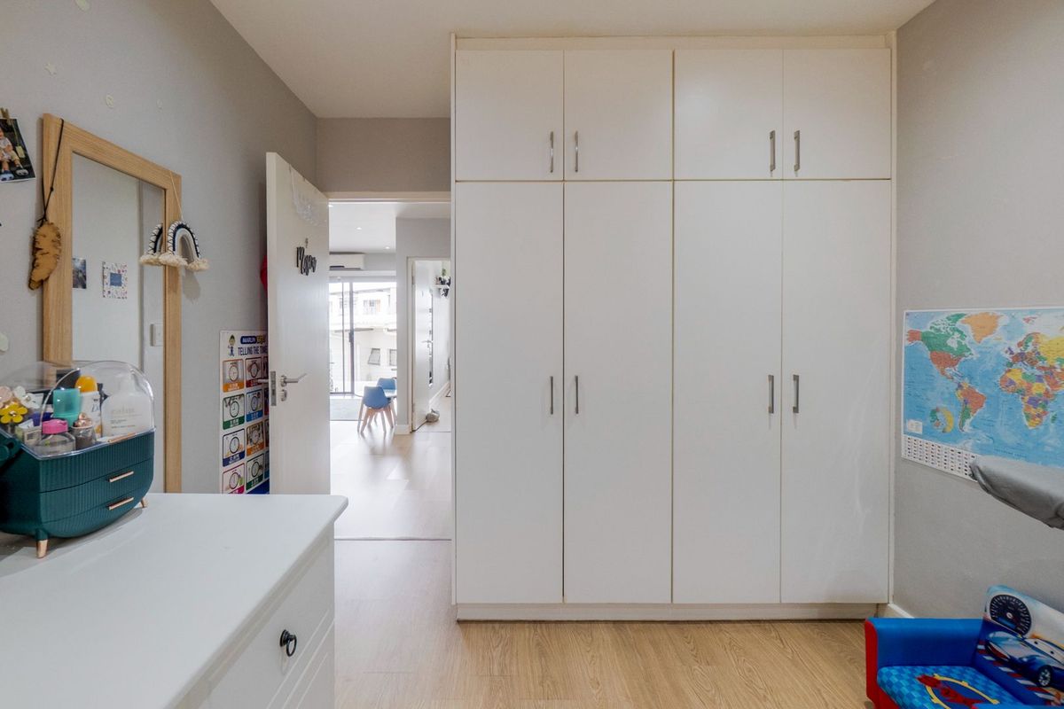A bedroom featuring built-in floor-to-ceiling white cabinetry with modern handles and light wood-look flooring.