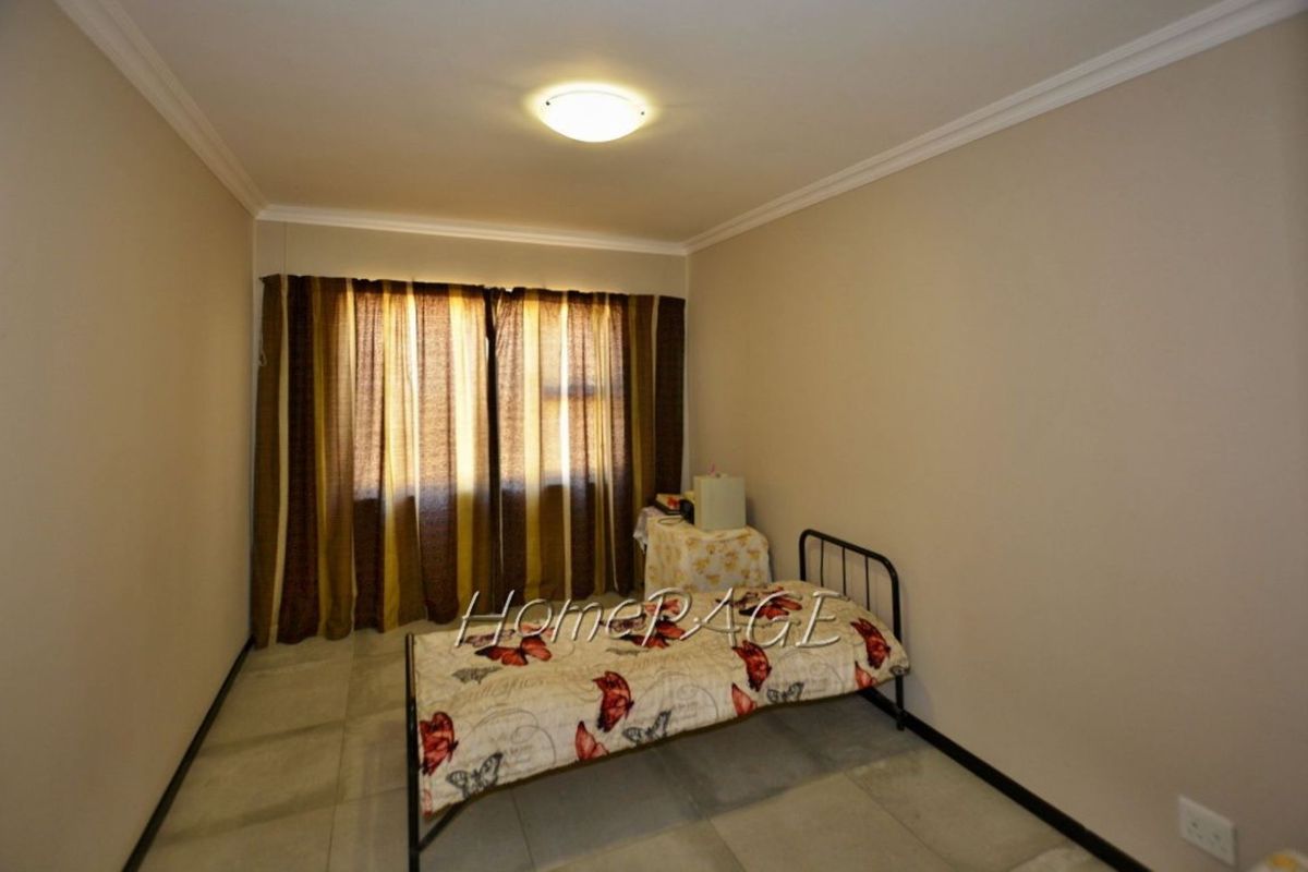A simple bedroom featuring neutral wall tones, tiled flooring, and a ceiling-mounted light fixture.