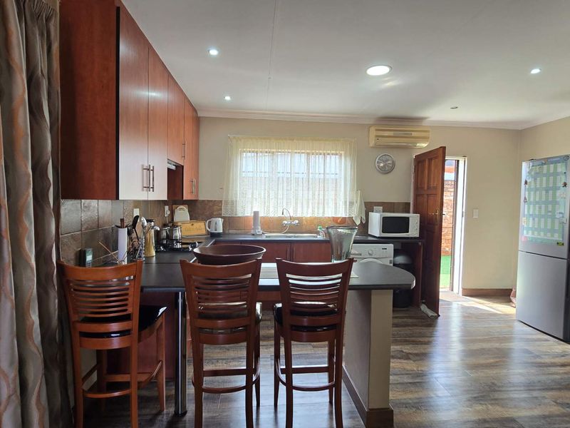 Functional kitchen featuring wood-finish cabinetry, laminate countertops, tiled backsplash, and recessed lighting, with direct access to the exterior.