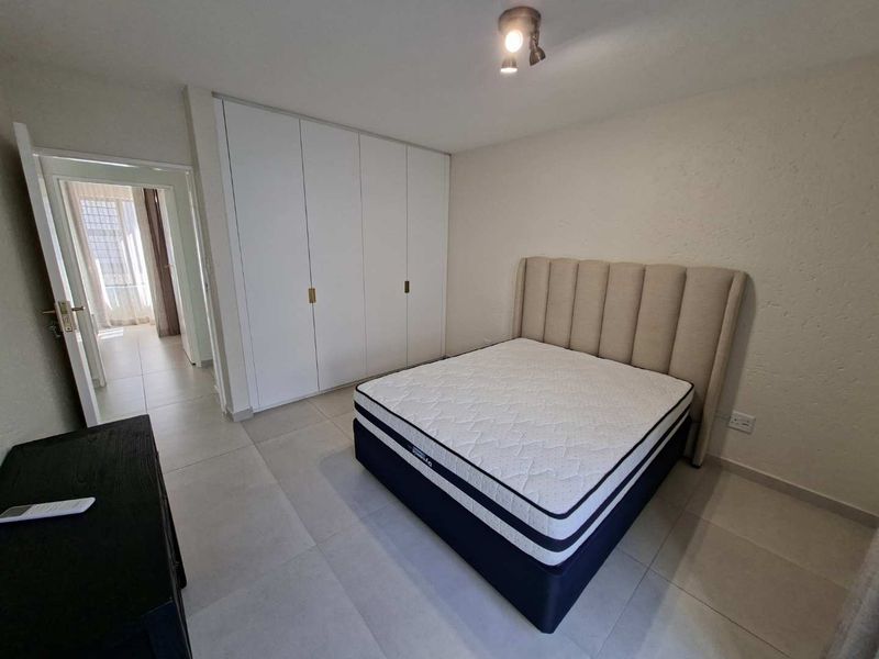 A well-maintained bedroom featuring neutral tiled flooring and ample built-in cupboard storage, offering a clean and functional living space.