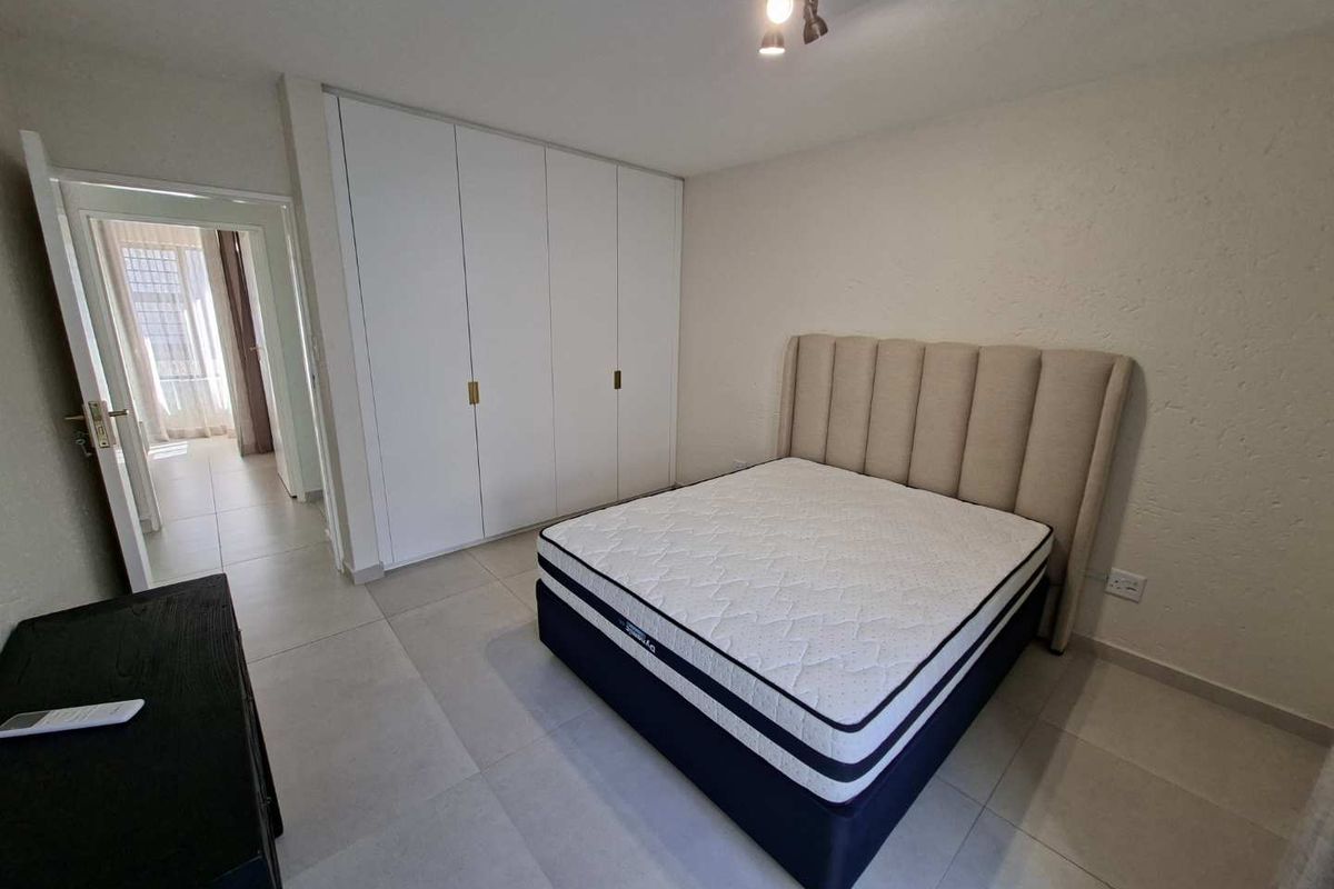 A well-maintained bedroom featuring neutral tiled flooring and ample built-in cupboard storage, offering a clean and functional living space.