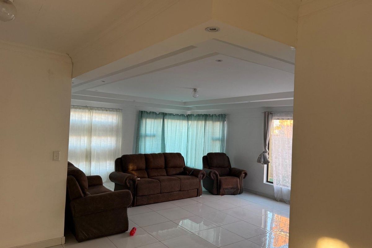 Spacious living room featuring large format floor tiles, a recessed ceiling design with downlights, and ample natural light through multiple windows.