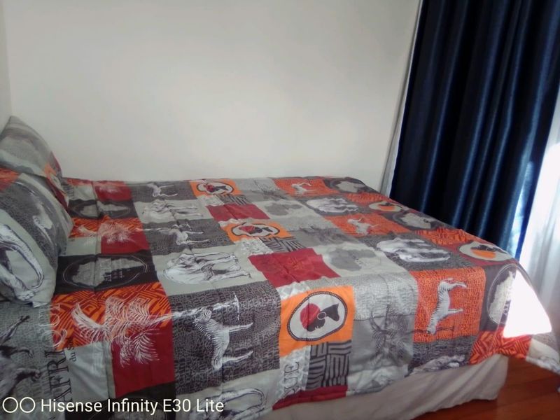 A bedroom featuring a bed positioned against a plain wall with dark curtains.