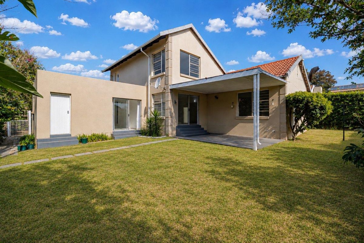 Rear view of the house featuring a covered patio area, lawn, and access to the interior through sliding glass doors.