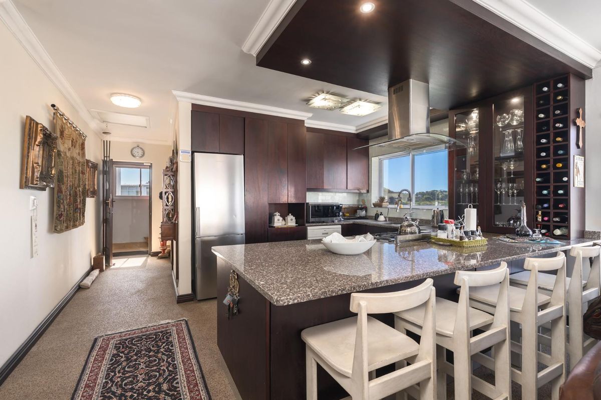 A well-appointed kitchen featuring dark wood cabinetry, granite countertops, a central island with breakfast bar seating, and a built-in wine rack.