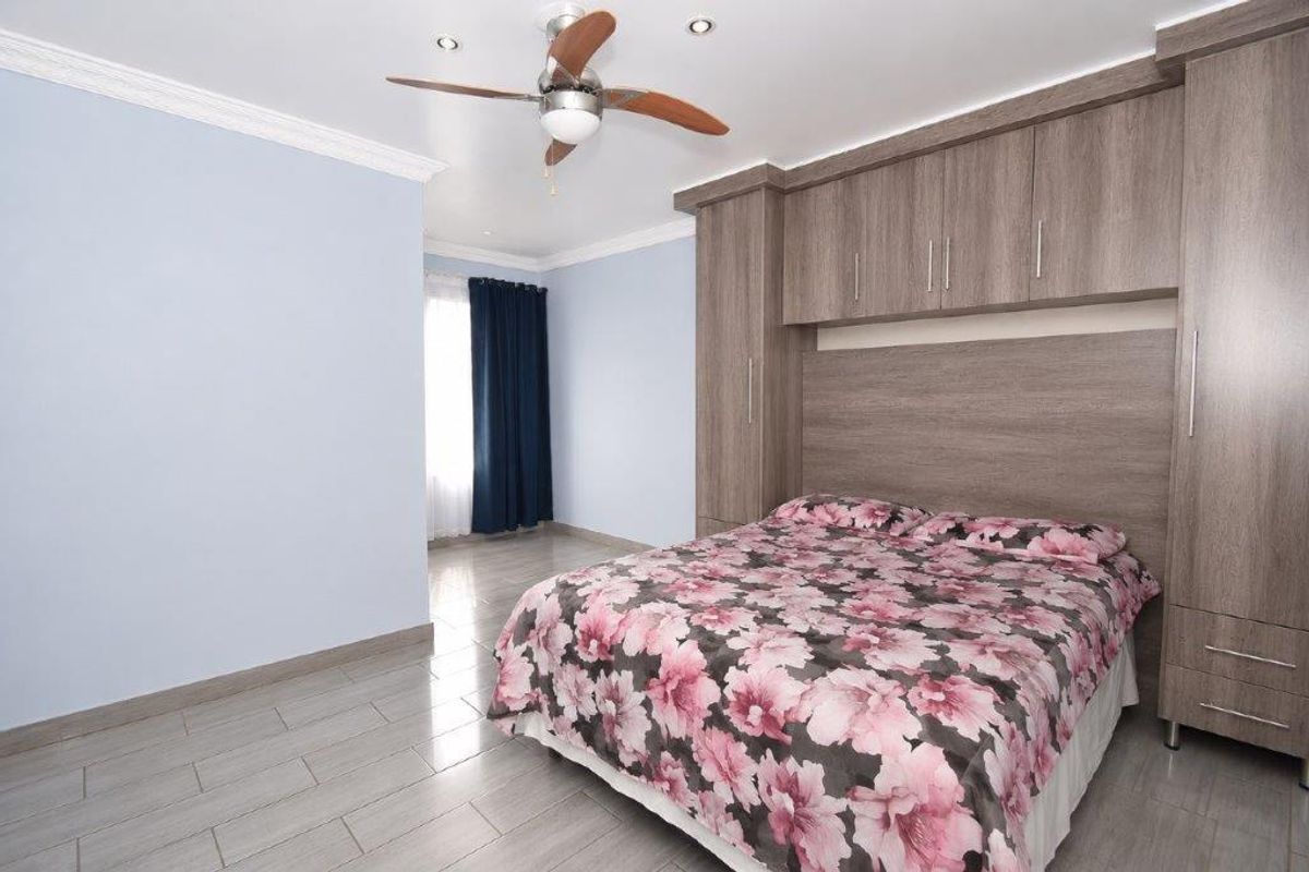 A well-maintained bedroom featuring built-in wooden cabinetry, overhead storage, a ceiling fan, and tiled flooring.