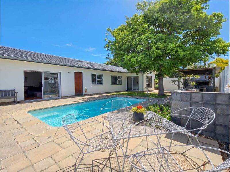 A well-maintained outdoor area featuring a swimming pool, paved patio, and a built-in braai, perfect for entertaining and relaxation.