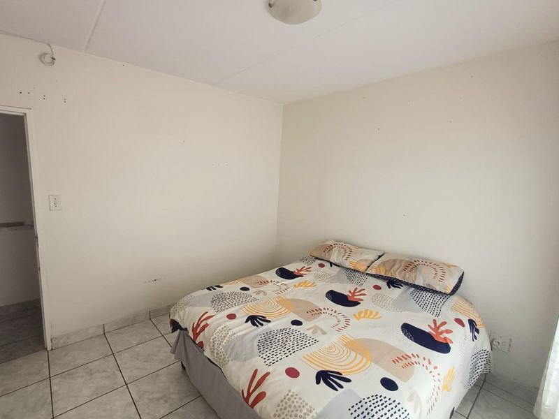 A simple bedroom featuring tiled flooring and neutral walls, offering a blank canvas for personalization and interior design updates.