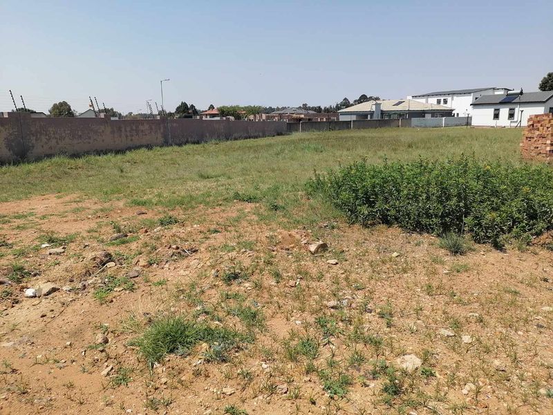 A vacant residential plot featuring a perimeter wall with electric fencing, offering a clear space ready for development.