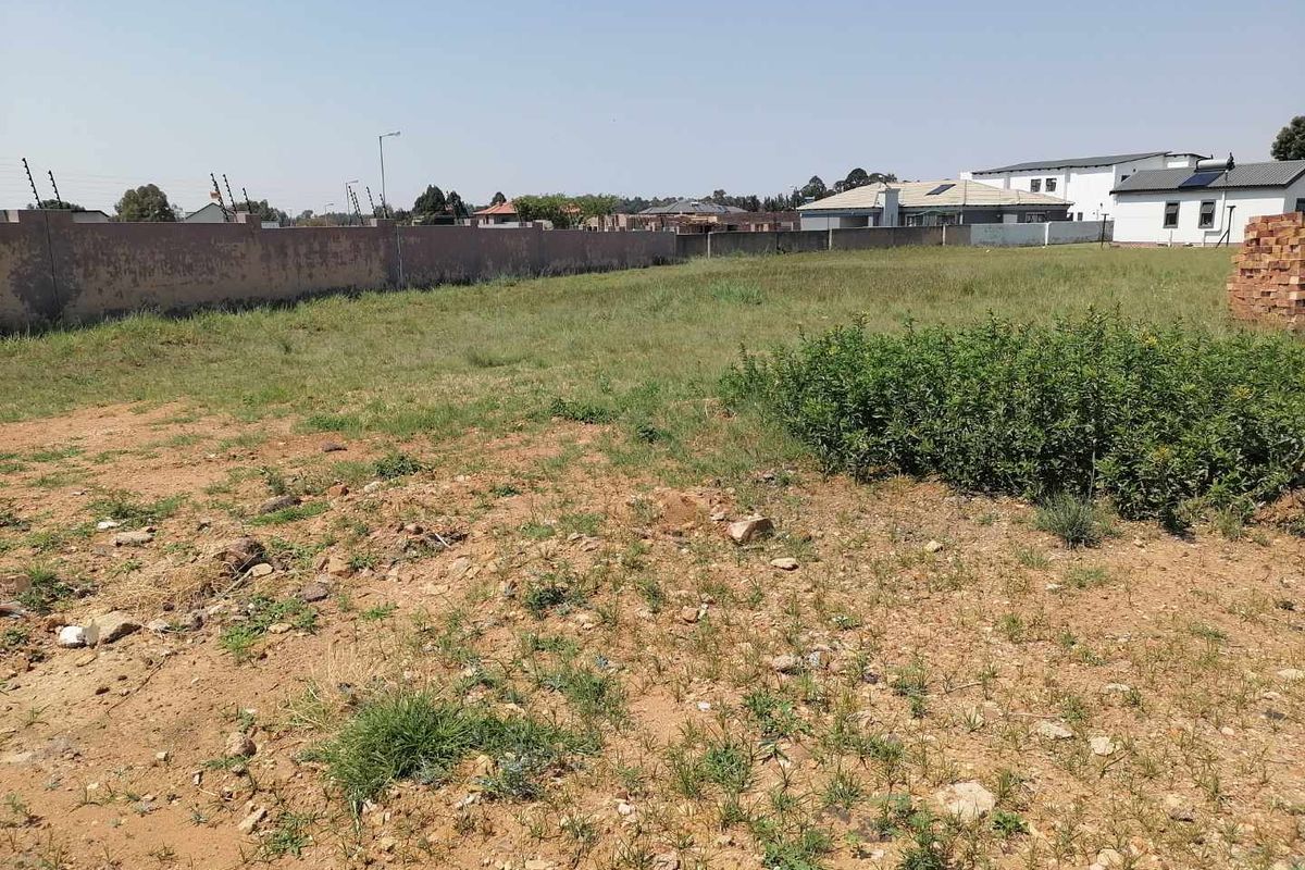A vacant residential plot featuring a perimeter wall with electric fencing, offering a clear space ready for development.
