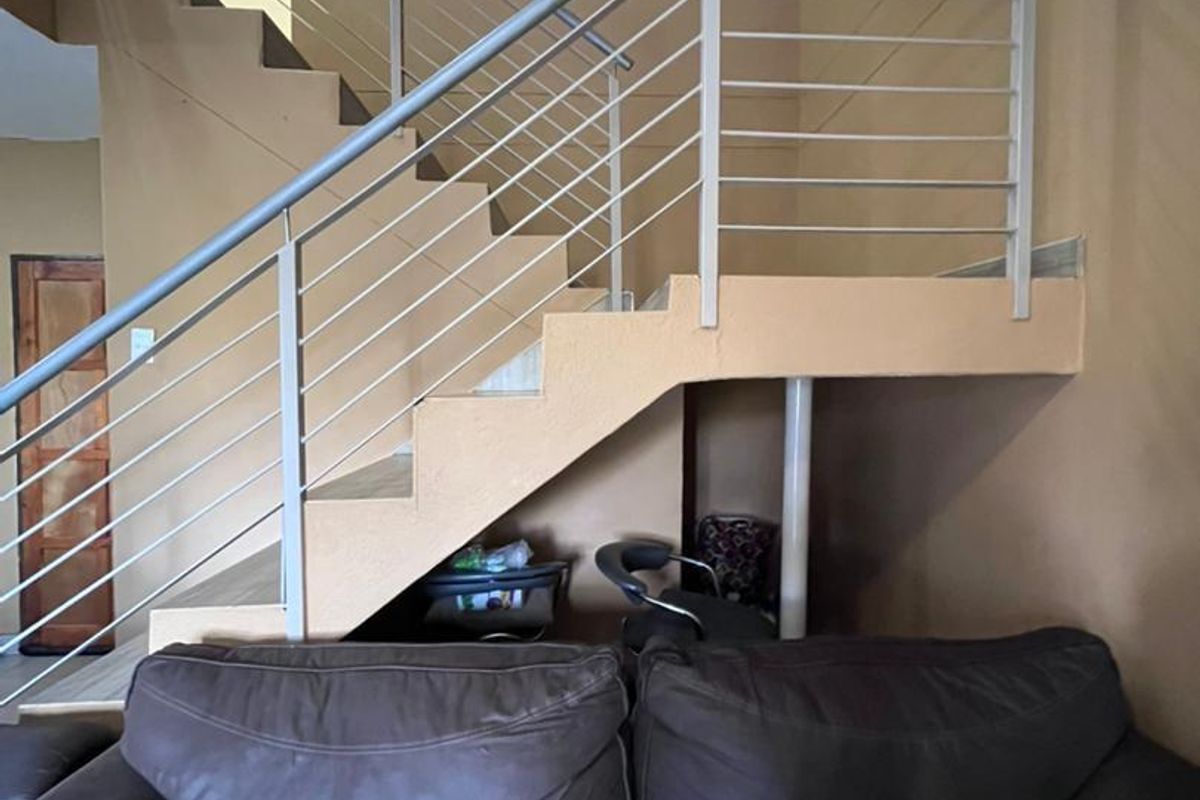 Interior view of a living area featuring a central staircase with modern metal railings and neutral wall tones.