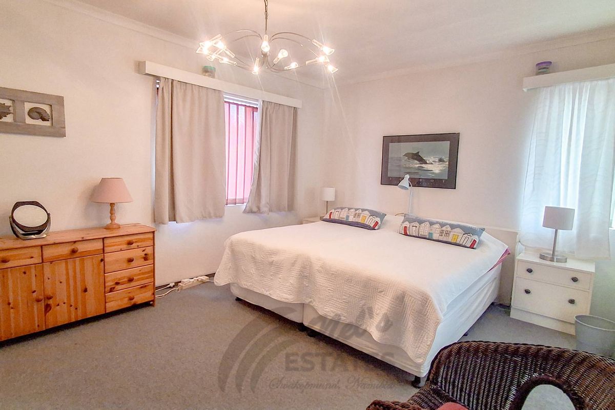 A spacious bedroom featuring neutral walls, carpeted flooring, and natural light through windows with fitted curtain rods.