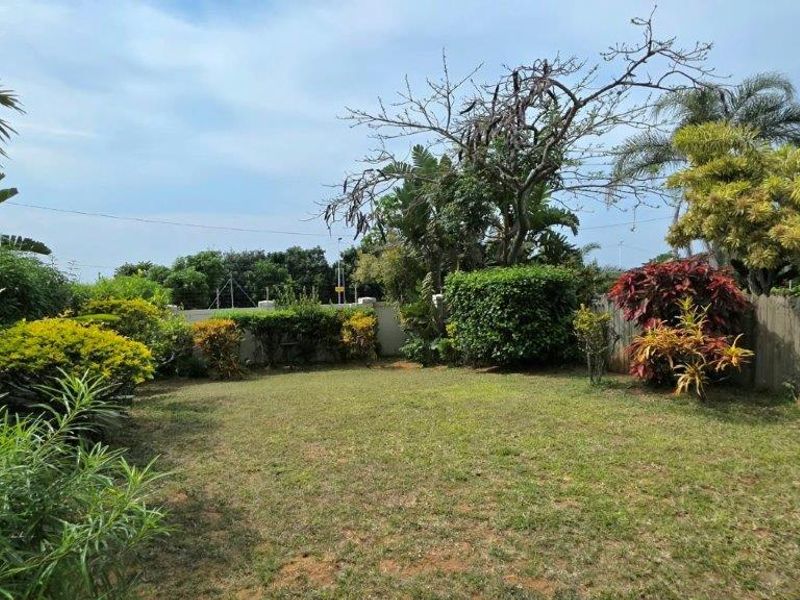 A private garden area featuring established landscaping, mature trees, and a combination of wooden fencing and boundary walling.