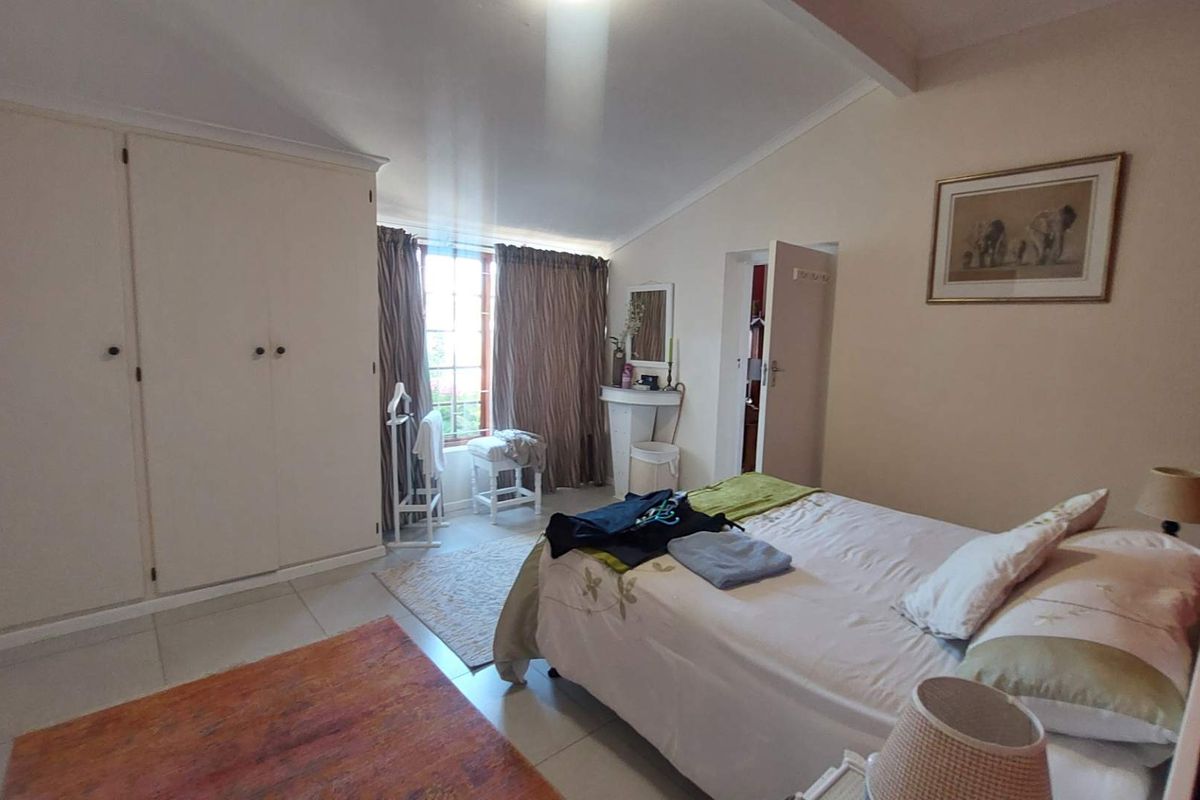 A well-lit bedroom featuring built-in cupboards, tiled flooring, and a window with curtains, offering a comfortable and functional living space.