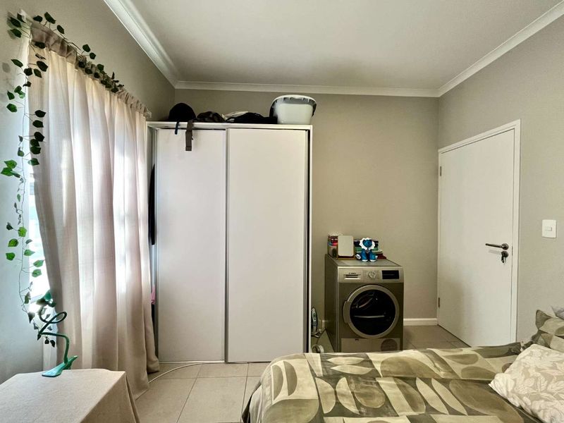 A bedroom featuring tiled flooring, a built-in wardrobe, and neutral wall finishes, providing a functional and well-lit living space.
