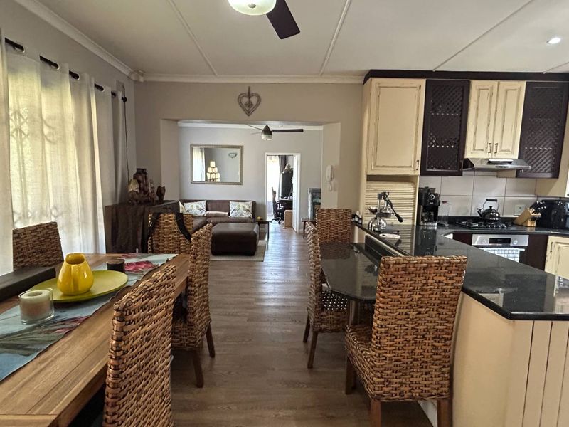Open-plan living and kitchen area featuring dark granite countertops, built-in cabinetry, and laminate flooring, creating a functional and connected space.