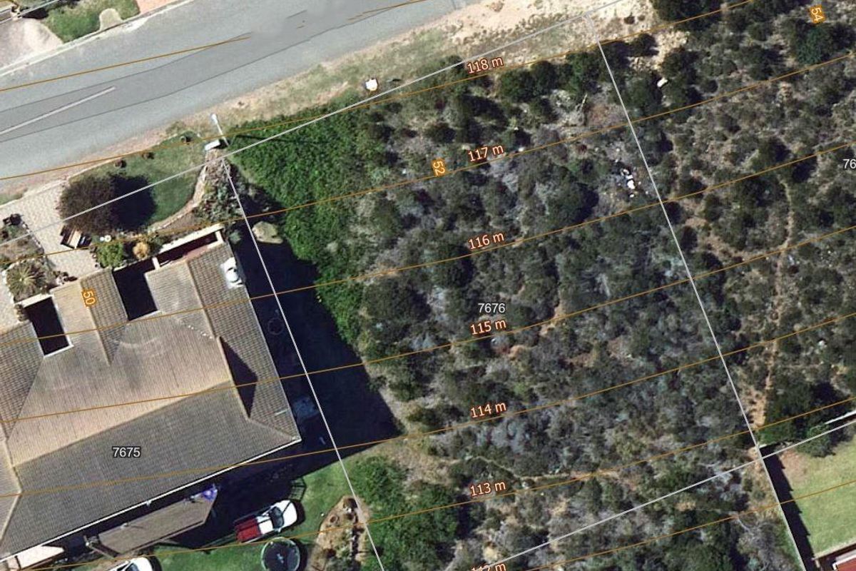 An aerial view of a vacant residential plot featuring natural vegetation and clearly marked boundary lines.
