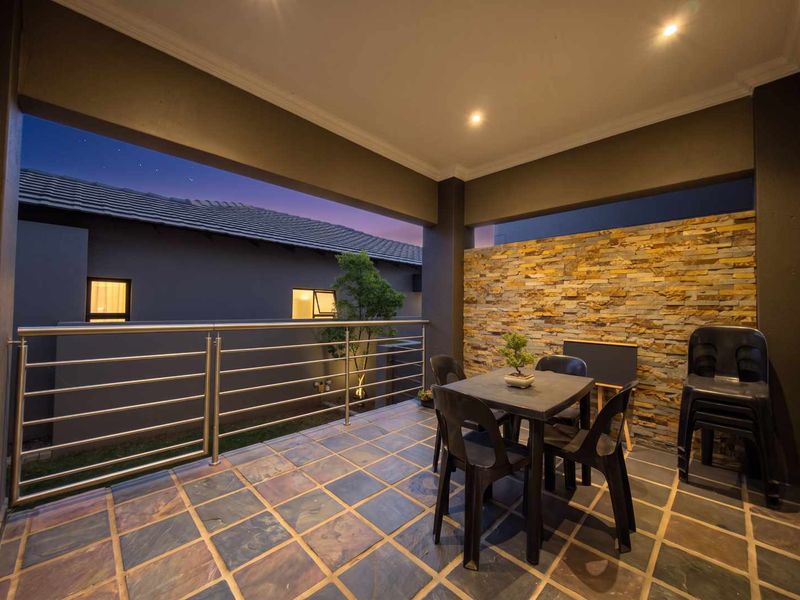 Covered patio featuring a decorative stone cladding wall, stainless steel balustrade, and durable tiled flooring, perfect for outdoor entertaining.
