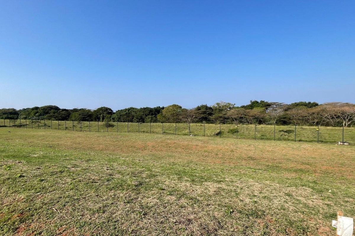 A clear, level plot of vacant residential land featuring perimeter fencing and a natural green outlook.