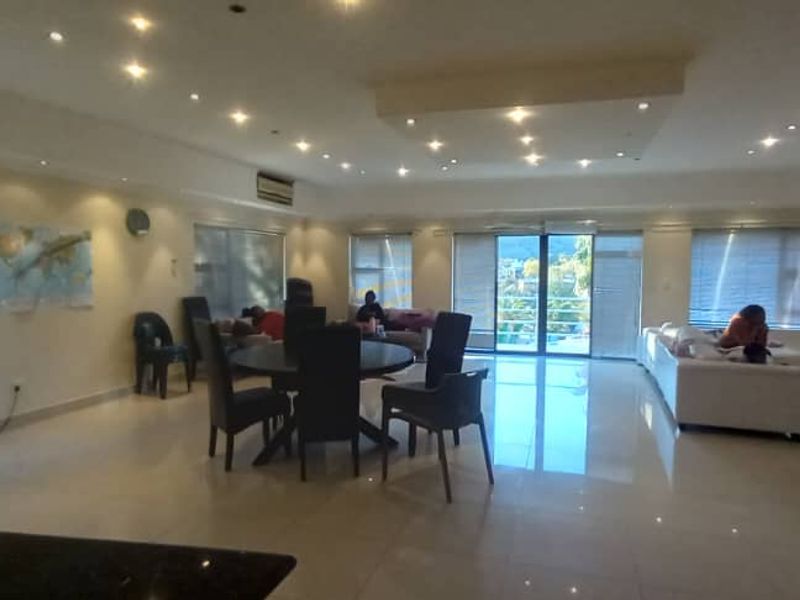 Spacious open-plan living area featuring tiled flooring, recessed ceiling lighting, and large sliding glass doors leading to an outdoor space.