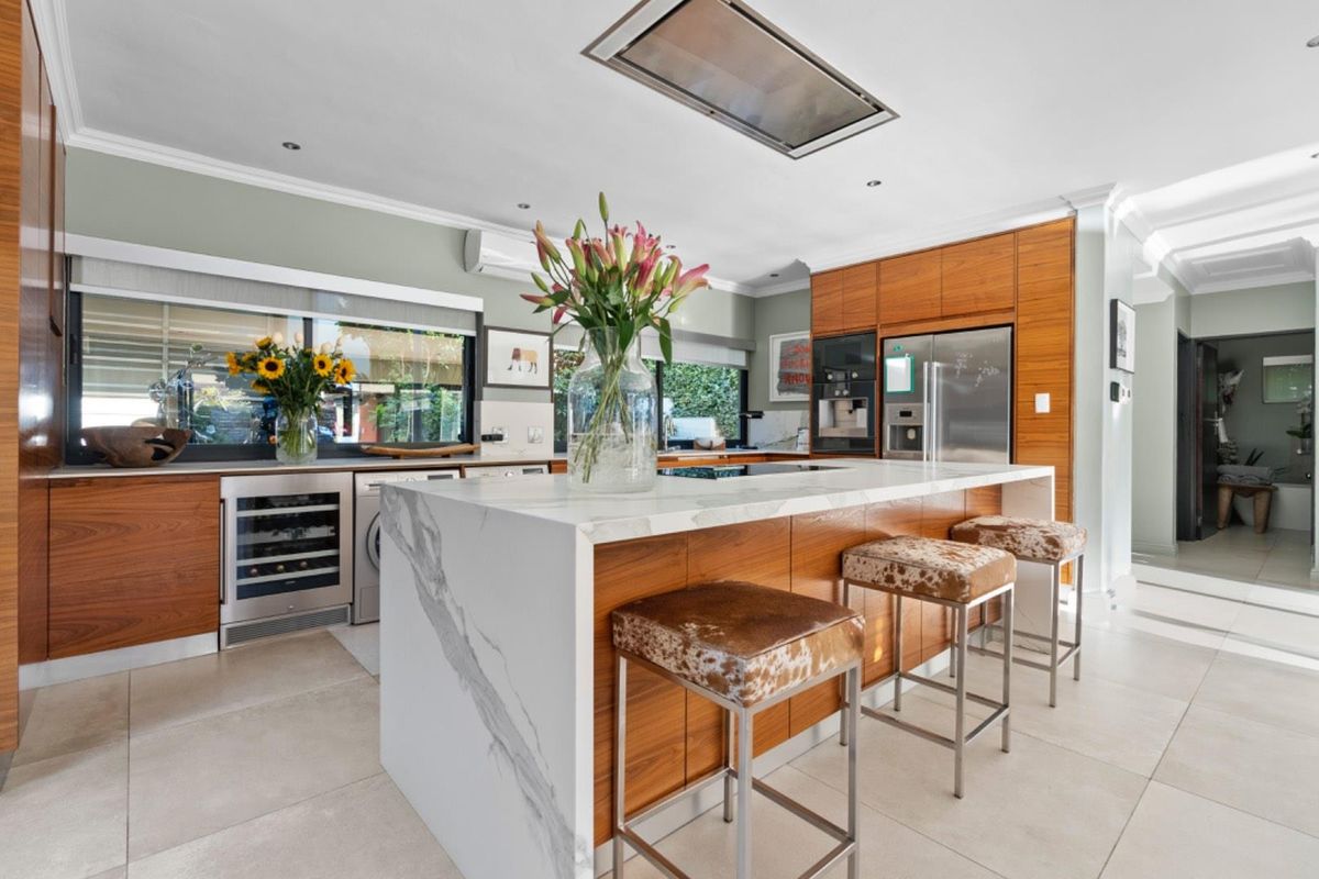 Modern kitchen featuring a large stone waterfall island, integrated cabinetry, high-end built-in appliances, and sleek tiled flooring.