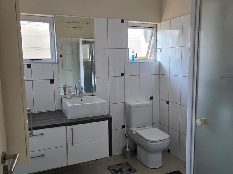 A functional bathroom featuring a wall-mounted vanity with a vessel sink, a toilet, and a separate shower enclosure with tiled finishes.