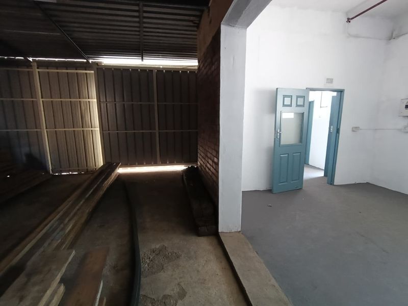 Industrial utility space featuring a combination of covered outdoor storage area and an enclosed room with painted concrete floors and exposed brickwork.