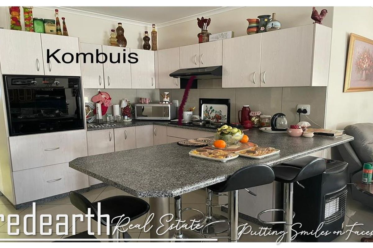 A functional kitchen featuring light-toned laminate cabinetry, granite countertops, a built-in oven, and an integrated breakfast bar for casual dining.