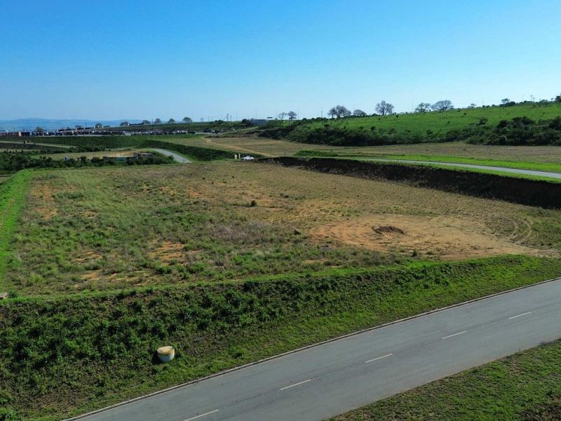 Aerial view of a vacant industrial land parcel featuring a graded platform, retaining embankments, and direct access to a paved road.