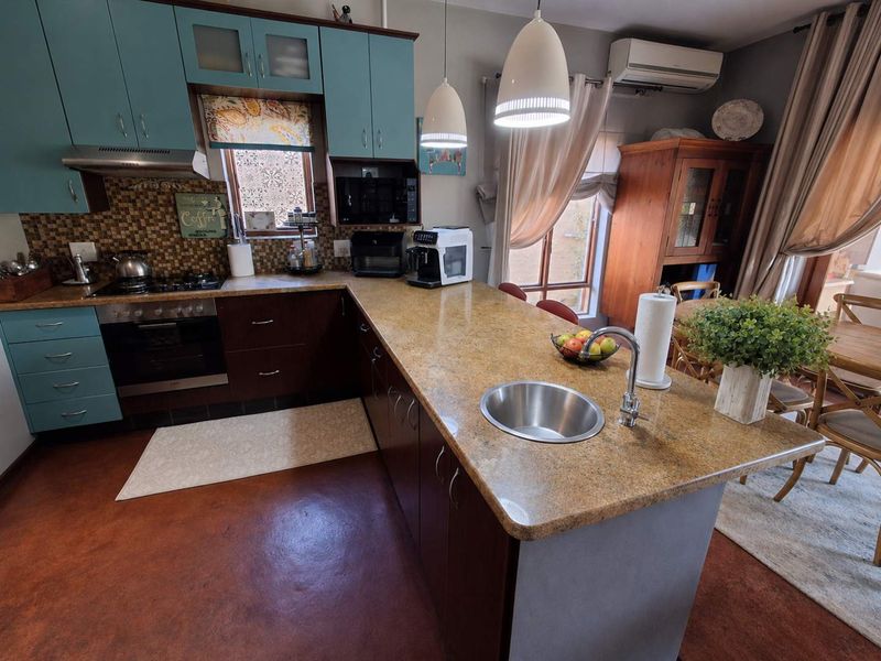 A functional kitchen featuring granite countertops, a central island with a prep sink, built-in oven, gas hob, and ample cabinetry.