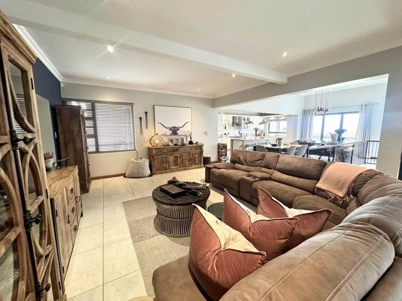 Spacious open-plan living area featuring tiled floors, recessed lighting, and a seamless flow into the modern kitchen and dining space.