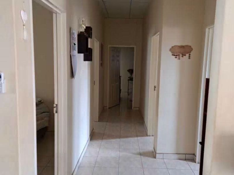 A functional hallway featuring tiled flooring and a suspended ceiling, providing access to multiple rooms within the property.