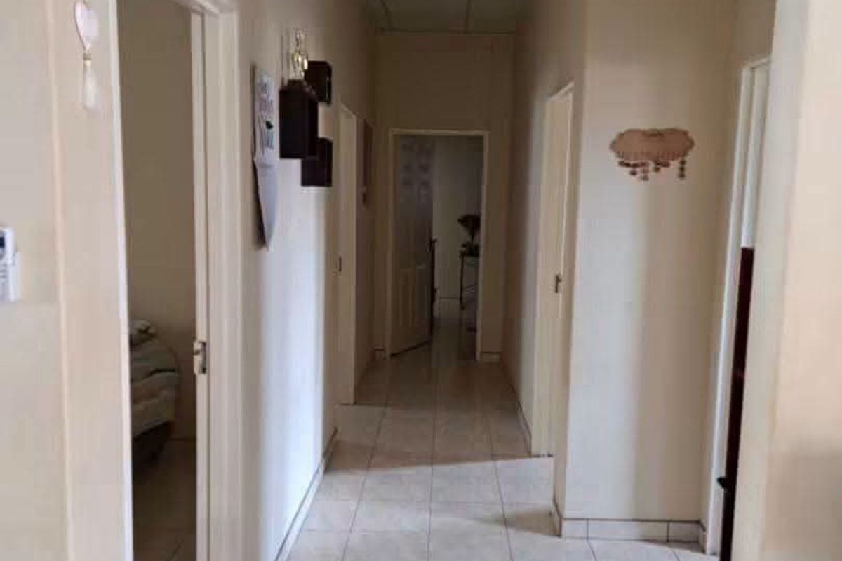 A functional hallway featuring tiled flooring and a suspended ceiling, providing access to multiple rooms within the property.