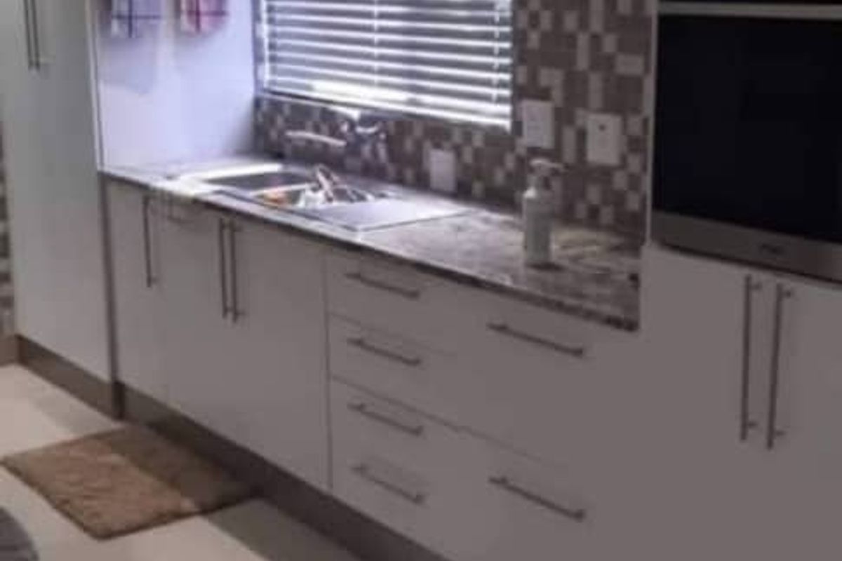 Modern kitchen featuring white cabinetry, stone countertops, mosaic tile backsplash, and integrated stainless steel oven and microwave.