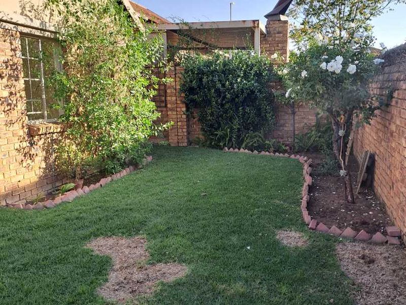 A private rear garden featuring a lawn area, brick boundary walls, and a brick chimney structure.