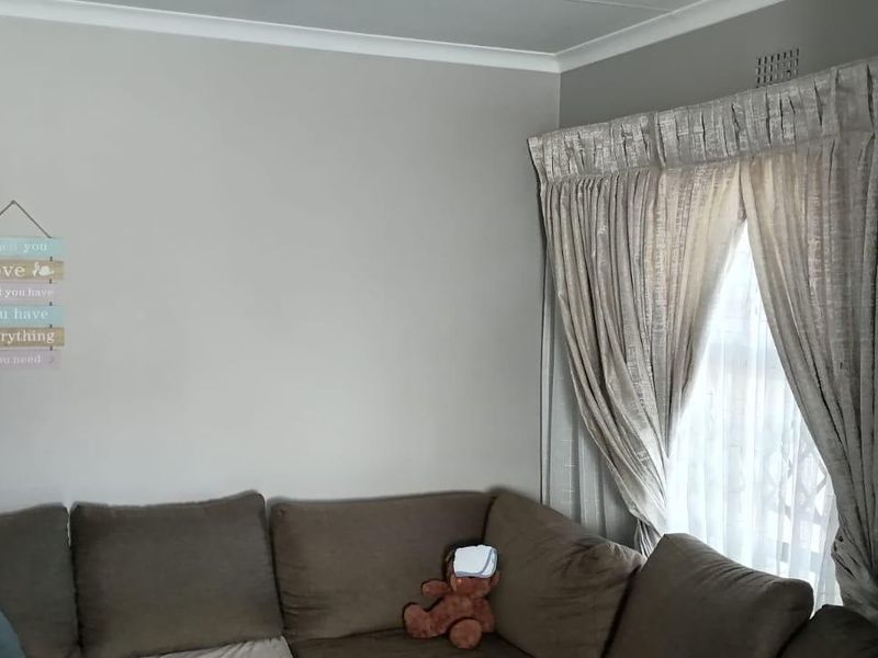 A living room area featuring neutral wall paint, cove cornicing, and window treatments.